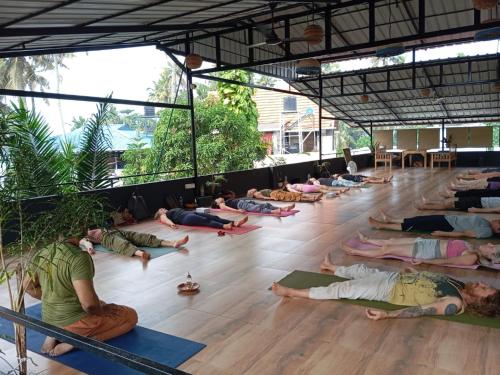 a group of people laying on the floor doing yoga at Mad about Coco Yoga & Beach Retreat in Varkala