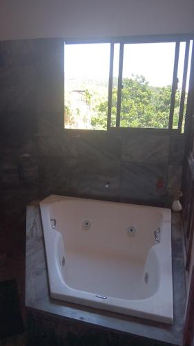a large white bath tub in a bathroom with a window at Casa Magia in Bombinhas