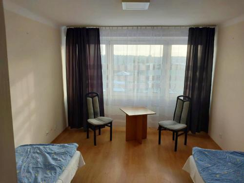 Cette chambre comprend deux lits, une table et des chaises. dans l'établissement Pokoje Urzędnicza Kielce, à Kielce