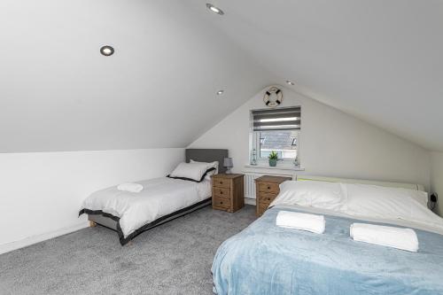 a attic bedroom with two beds and a window at Clydfan, No 1 Trearddur Road in Trearddur