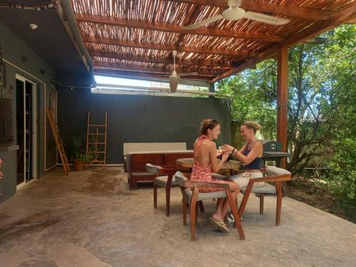 dos mujeres sentadas en una mesa en un patio en L2 Bacalar en Bacalar