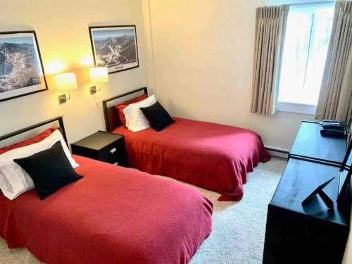 a hotel room with two beds with red sheets at Mt Green, Pool, Gym, Sauna, Hot Tub Open 3br2b, in Killington