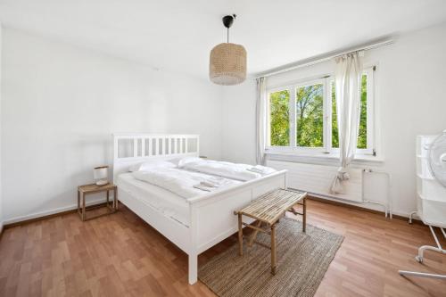 a white bedroom with a bed and a window at Homey Comfort in Oerlikon in Zürich