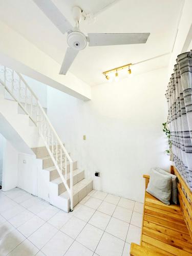 a white living room with stairs and a ceiling at Nomads MNL Backpackers Homestay - near Airport in Manila