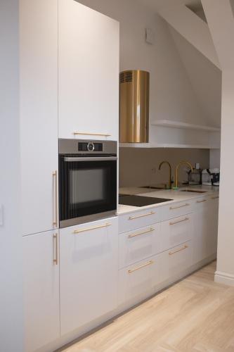a kitchen with white cabinets and a microwave at Srebrna Luxury Apartments - willa fabrykancka - wnętrza premium in Łódź