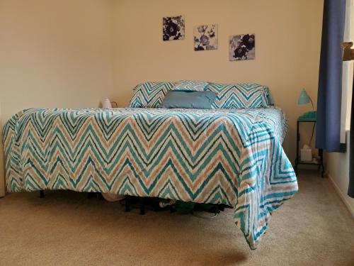 a bed with a striped comforter in a bedroom at Not Vegas, But Close Enough in Boulder City