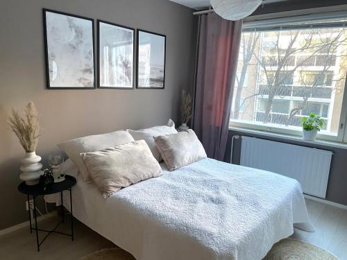 1 dormitorio con 1 cama con sábanas blancas y ventana en Avara keskusta asunto + oma ilmainen parkkipaikka en Tampere