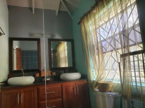 a bathroom with two sinks and a large window at Nia's Hillside Loft - Exquisite Views in Gros Islet