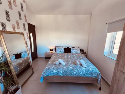Schlafzimmer mit einem Bett und einem Spiegel in der Unterkunft LA88 SweetHome Penthouse with Jacuzzi in San Ġwann