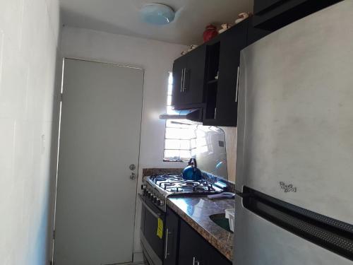 a small kitchen with a stove and a refrigerator at Hermosa y cómoda casita super cerca del Estadio El Kraken in Mazatlán