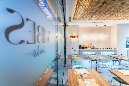 a restaurant with wooden tables and blue chairs at Hotel Málaga Vibes in Málaga
