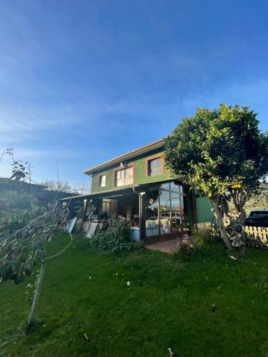 una casa seduta in cima a un rigoglioso campo verde di Eco-Hostel La Casa Verde a Poo de Llanes