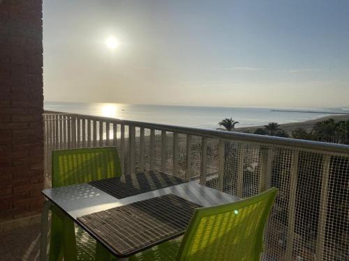 una mesa y sillas en un balcón con vistas al océano en Beachfront and Cozy Apartment, en Cullera