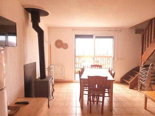 a dining room with a table and a wood stove at Appartement charmant à La Salvetat-sur-Aout 50 m² avec jardin in La Salvetat