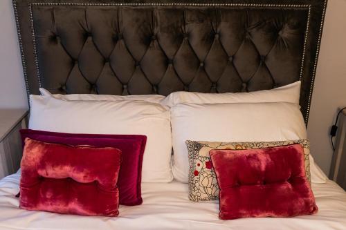 a bed with two red pillows and a black headboard at Carlton lodge at Carlton tavern free parking in York