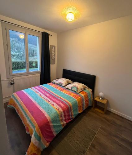 um quarto com uma cama com um cobertor colorido e uma janela em GITE LE MAGNOLIA em Voiteur
