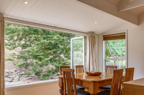 a dining room with a table and a large window at Arrow Junction Cottage in Arrowtown