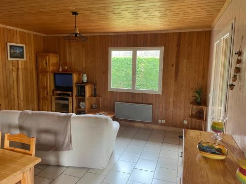 a living room with a white couch and a window at Maison dans une bulle de verdure in Lacanau