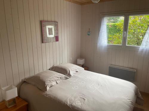 - une chambre avec un lit avec deux oreillers et une fenêtre dans l'établissement Maison dans une bulle de verdure, à Lacanau