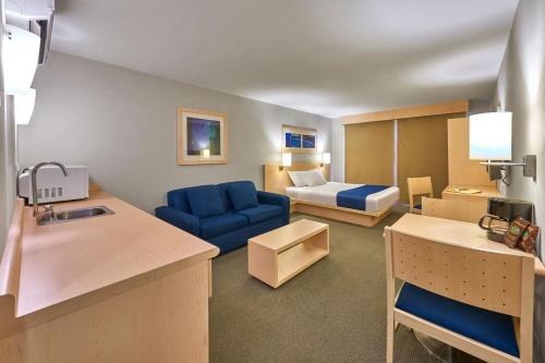 a hotel room with a blue couch and a bed at City Express by Marriott Apizaco in Apizaco