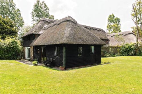 an old house with a thatched roof in a yard at Parsonage Barn Annex in Winchelsea