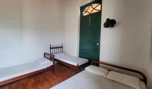 a room with two beds and a green door at Casa de Izaura in Lençóis