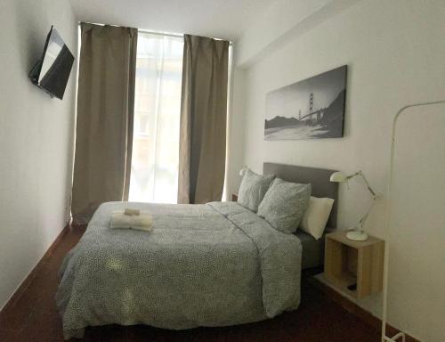 1 dormitorio con cama y ventana en Rooms Cáceres, en Madrid