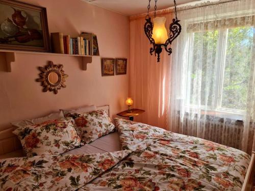 a bedroom with a bed with a floral comforter and a window at Romantic apartment in Fjälkinge