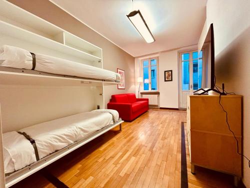 um quarto com 2 beliches e uma cadeira vermelha em Kibilù - Via Medaglie D'Oro Centro Città con Parcheggio em Varese