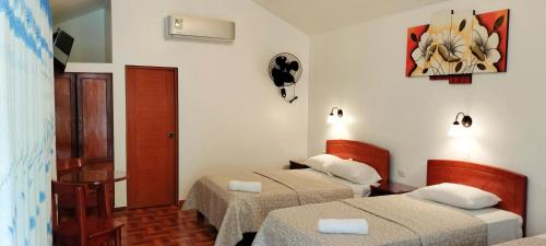 a room with two beds and a clock on the wall at Hotel El Tirol in San Ramón