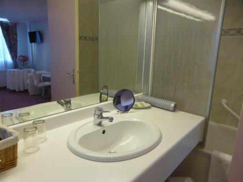 La salle de bains est pourvue d'un lavabo et d'un miroir sur un comptoir. dans l'établissement Logis - Hostellerie & Restaurant Saint Louis, à Bollezeele