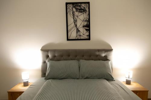 a bedroom with a bed with two lamps and a picture at Horizon Grey Apartment & Spa in Skopje