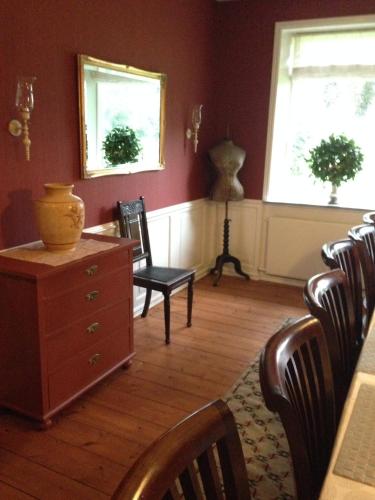 a living room with a dresser and chairs and two windows at Birkende Bed and Breakfast in Langeskov