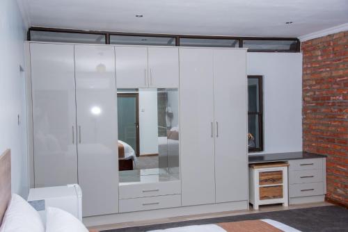 um quarto com armários brancos e uma parede de tijolos em Boruundi Private Lodge & Campsite em Bokaa