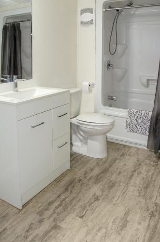 a white bathroom with a toilet and a shower at Prospectors Inn in Kirkland Lake