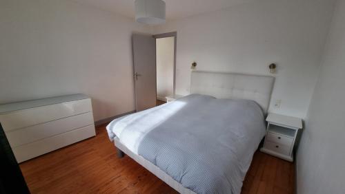 1 dormitorio con cama blanca y suelo de madera en Maison 2 chambres proche base, en Mont-de-Marsan