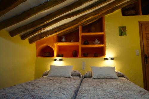 two beds in a bedroom with yellow walls at Casa Rural Manubles in Bijuesca