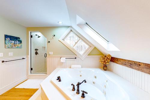 a bathroom with a large white tub and a skylight at Mad River SpaCasa in Waitsfield