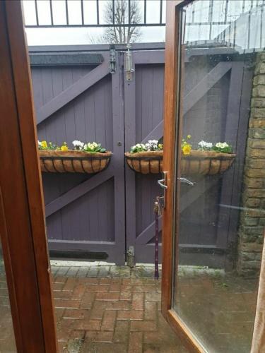 uma porta com duas cestas de flores numa garagem em Private double bedroom ensuite with patio em Londres