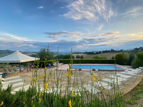 a swimming pool with a white tent and a building at Il Melograno Country Resort in Grottazzolina
