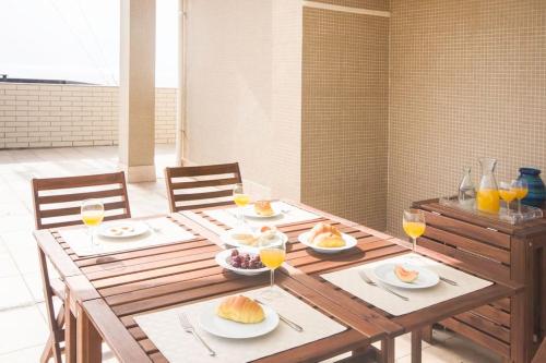 a wooden table with plates of food and glasses of orange juice at Sea View - Charming apartment in Vila do Conde