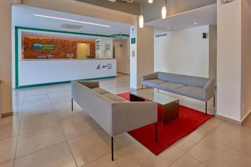 a lobby with two couches and a red rug at City Express Junior by Marriott Leon Centro de Convenciones in León