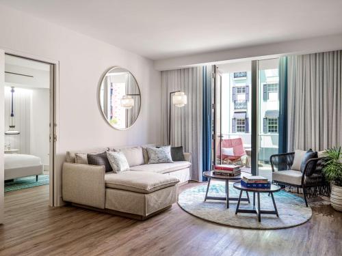 a living room with a couch and a table at The Ray Hotel Delray Beach, Curio Collection By Hilton in Delray Beach