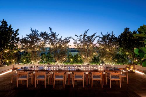 a long table and chairs on a patio with lights at The Ray Hotel Delray Beach, Curio Collection By Hilton in Delray Beach