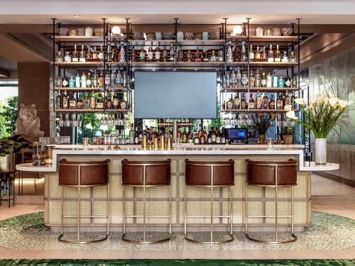 a bar with brown bar stools and a screen at The Ray Hotel Delray Beach, Curio Collection By Hilton in Delray Beach