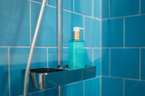 Baño de azulejos azules con una botella de jabón en un estante en Social Lodge - Piornais, en Funchal
