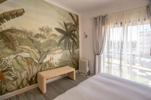 ein Schlafzimmer mit einem Gemälde an der Wand in der Unterkunft Apartamento acolhedor em Lagos in Lagos