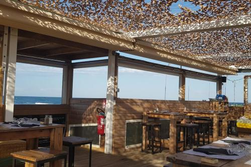 un restaurant avec des tables, des chaises et des fenêtres dans l'établissement Appartement Iris Résidence les Grenadines, à Gruissan