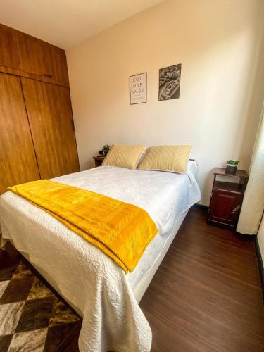 een slaapkamer met een bed met een gele deken erop bij Acogedor departamento céntrico in Cochabamba