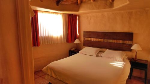 a bedroom with a white bed and a window at Los Colorados Cabañas Boutique in Purmamarca